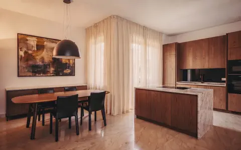 Zona giorno con credenza, tavolo ovale e cucina in rovere affumicato con isola in marmo