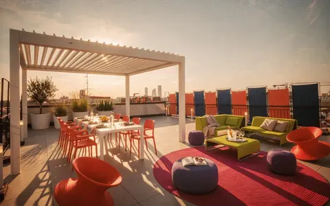 Terrazzo con pergola bioclimatica, divano Island di Paola Lenti e sedute Spun di Magis