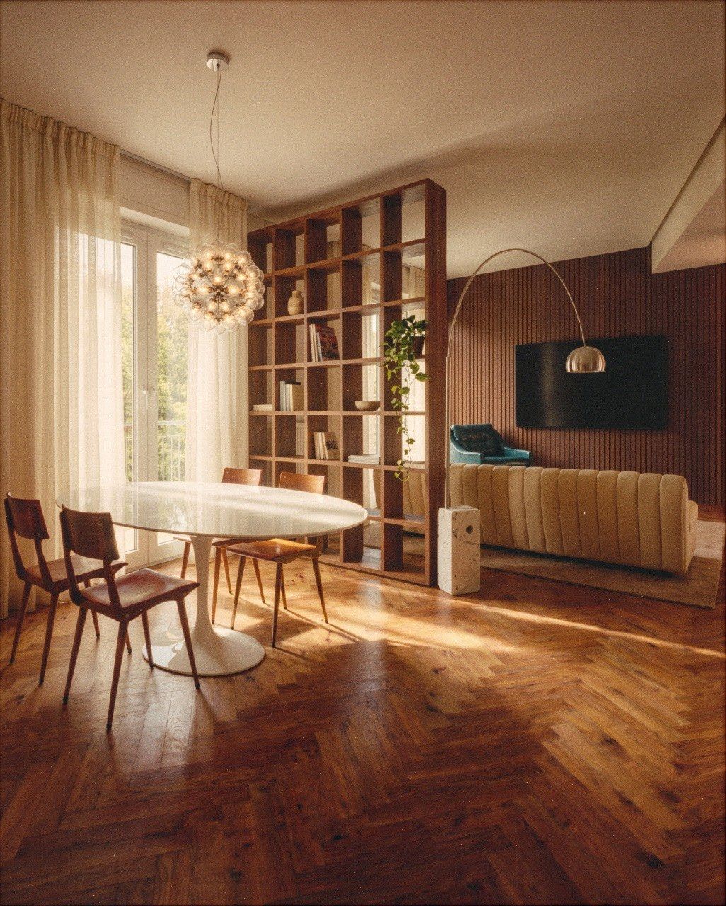 Rendering di una zona giorno con libreria divisoria in noce e parquet a spina di pesce
