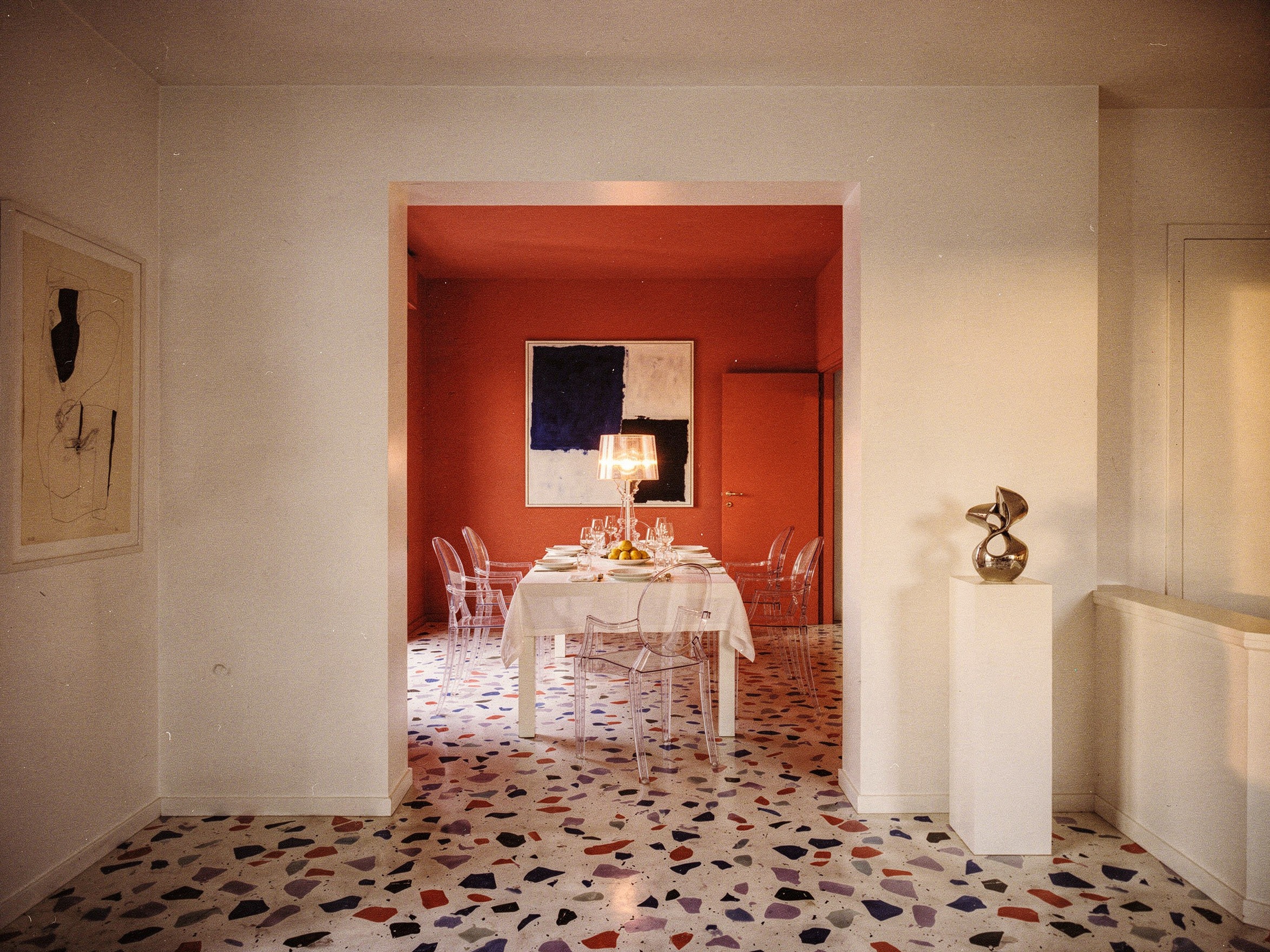 Sala da pranzo corallo con sedie Louis Ghost e lampada Bourgie di Kartell